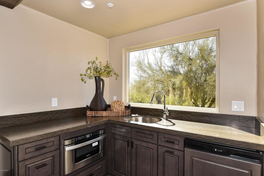 Small transitional l-shaped light wood floor eat-in kitchen photo in Phoenix with a farmhouse sink, raised-panel cabinets, brown cabinets, granite countertops, beige backsplash, ceramic backsplash, paneled appliances and an island