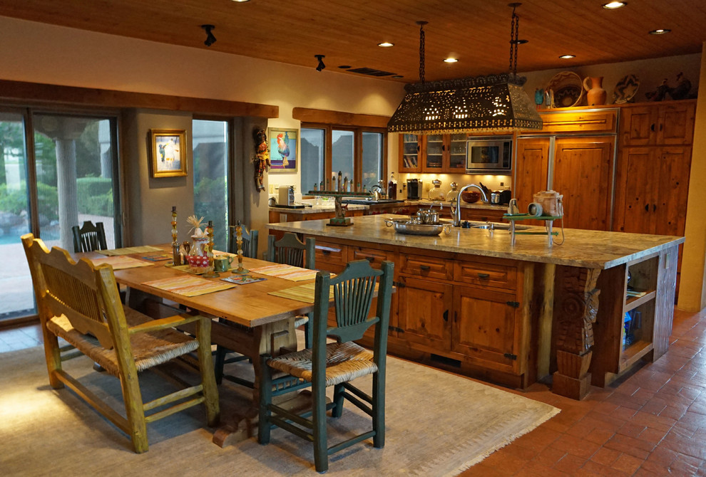 Inredning av ett rustikt stort kök, med en undermonterad diskho, luckor med upphöjd panel, skåp i mellenmörkt trä, granitbänkskiva, beige stänkskydd, stänkskydd i glaskakel, rostfria vitvaror, klinkergolv i terrakotta och en köksö