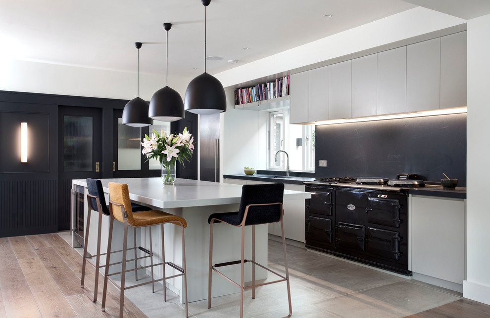Esempio di una cucina design con ante lisce, ante bianche, paraspruzzi nero, paraspruzzi in lastra di pietra, elettrodomestici neri, pavimento grigio e top nero