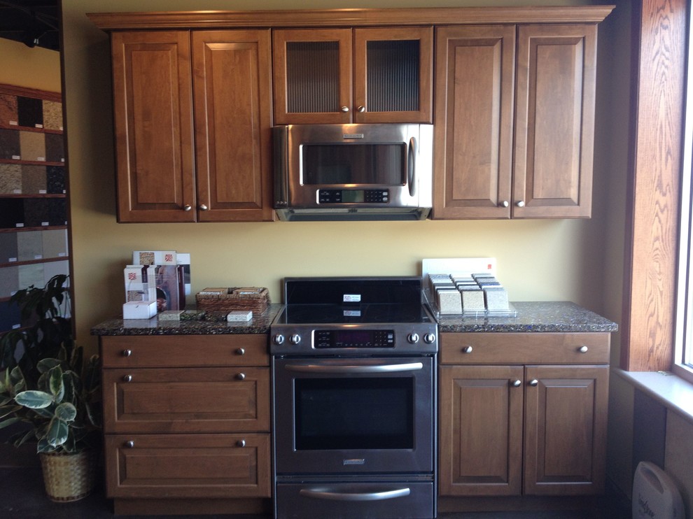 オマハにあるトラディショナルスタイルのおしゃれなI型キッチン (レイズドパネル扉のキャビネット、中間色木目調キャビネット、再生ガラスカウンター、シルバーの調理設備) の写真