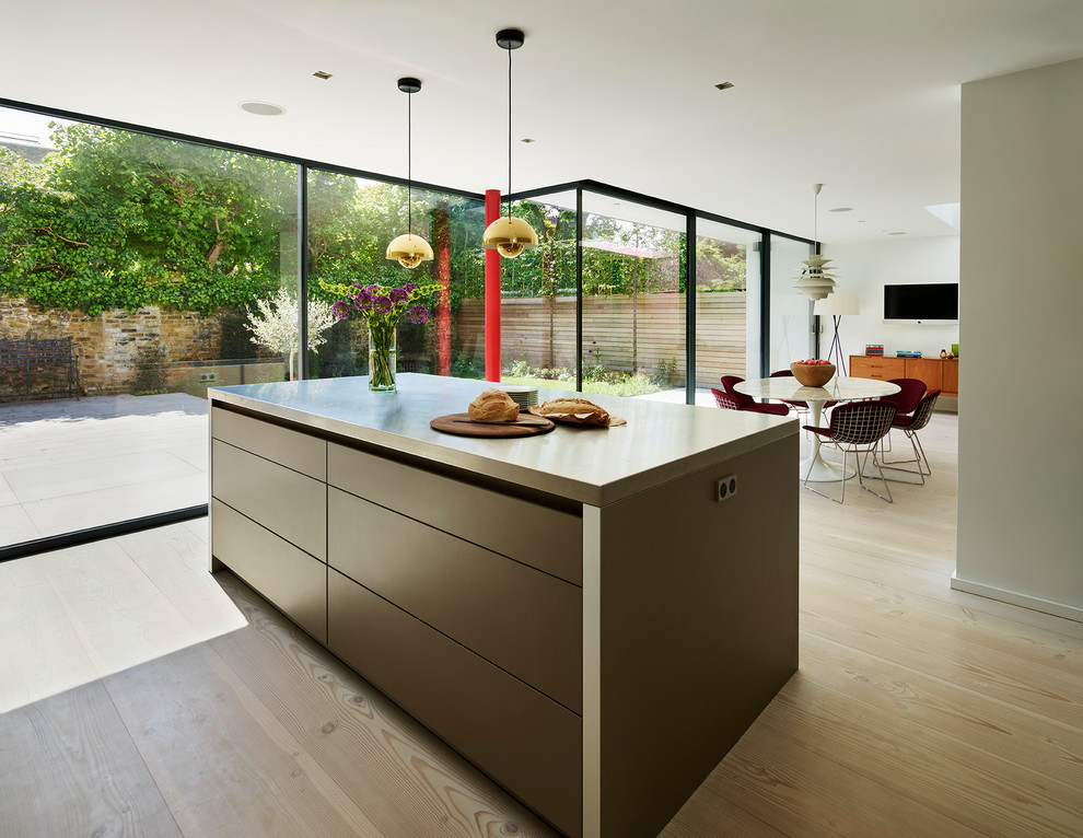 Foto på ett mellanstort funkis grå kök och matrum, med släta luckor, svarta skåp, bänkskiva i betong, ljust trägolv och en köksö