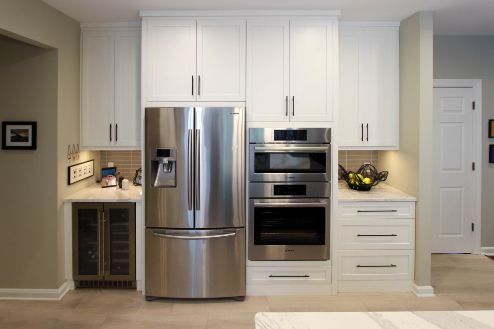 Example of a large transitional galley eat-in kitchen design in Cleveland with an undermount sink, recessed-panel cabinets, white cabinets, stainless steel appliances and an island