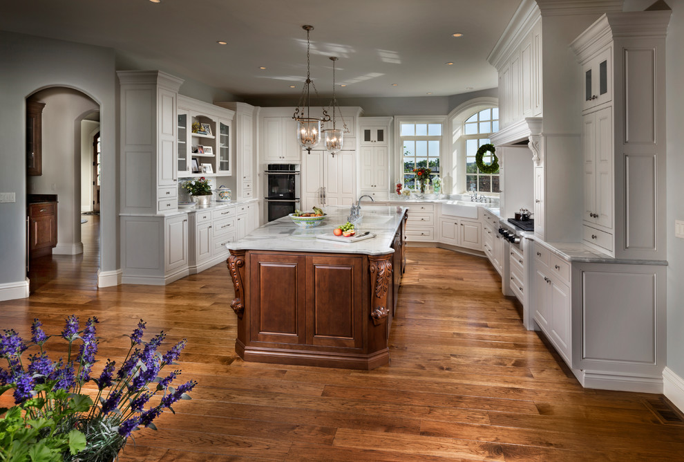 Exempel på ett stort klassiskt u-kök, med en rustik diskho, luckor med upphöjd panel, vita skåp, marmorbänkskiva, rostfria vitvaror, mellanmörkt trägolv, en köksö och brunt golv