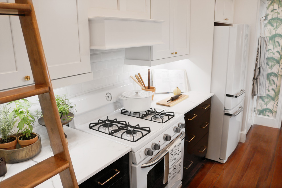 Large transitional single-wall dark wood floor and brown floor enclosed kitchen photo in DC Metro with shaker cabinets, white cabinets, marble countertops, white backsplash, subway tile backsplash, white appliances and no island