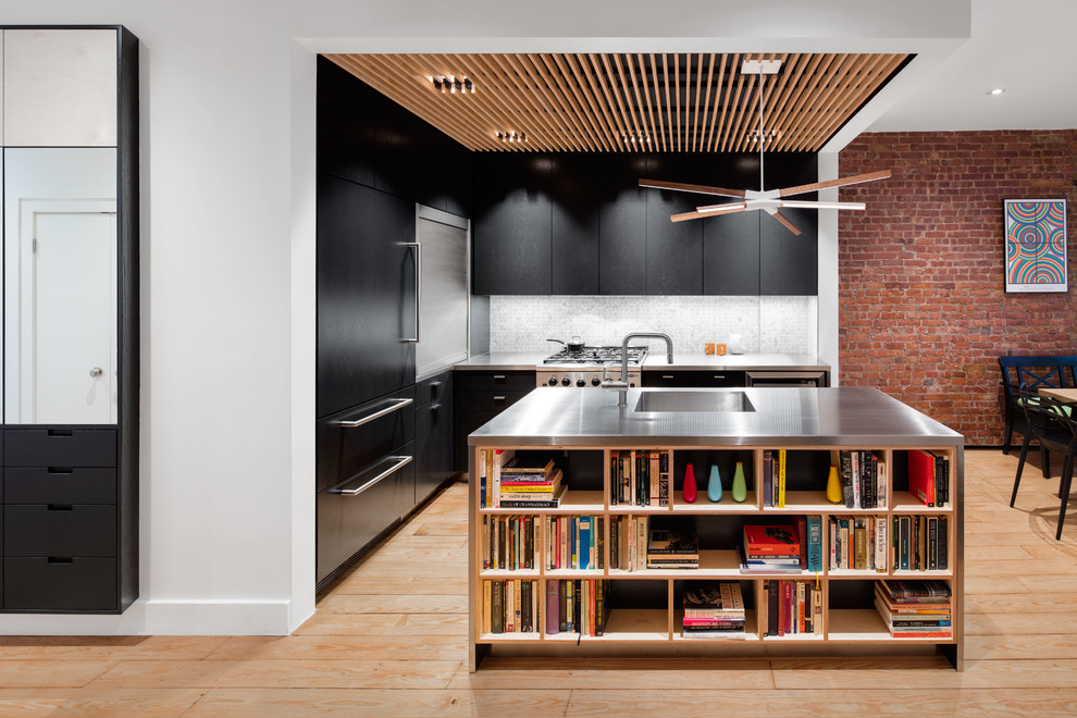 Eat-in kitchen - mid-sized contemporary u-shaped light wood floor eat-in kitchen idea in New York with an integrated sink, flat-panel cabinets, black cabinets, stainless steel countertops, white backsplash, stone tile backsplash, an island and paneled appliances