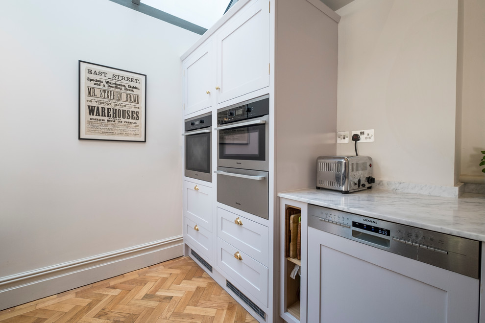 Traditional l-shaped open plan kitchen in Cardiff with a submerged sink, shaker cabinets, brown cabinets, marble worktops, stainless steel appliances, medium hardwood flooring and an island.