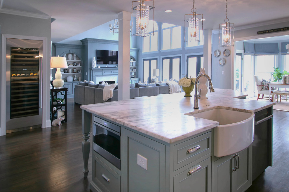 Example of a large trendy medium tone wood floor eat-in kitchen design in Charlotte with a farmhouse sink, flat-panel cabinets, white cabinets, marble countertops, gray backsplash, stainless steel appliances and an island