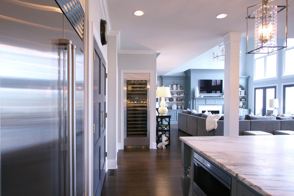 Modern inredning av ett stort kök och matrum, med en rustik diskho, släta luckor, vita skåp, marmorbänkskiva, grått stänkskydd, rostfria vitvaror, mellanmörkt trägolv och en köksö