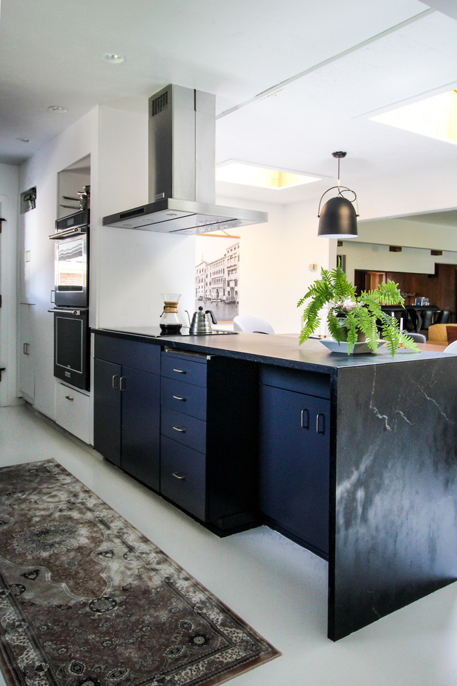 Photo of a medium sized scandinavian galley kitchen/diner in Boise with a belfast sink, flat-panel cabinets, grey cabinets, soapstone worktops, white splashback, window splashback, black appliances, painted wood flooring, a breakfast bar and white floors.