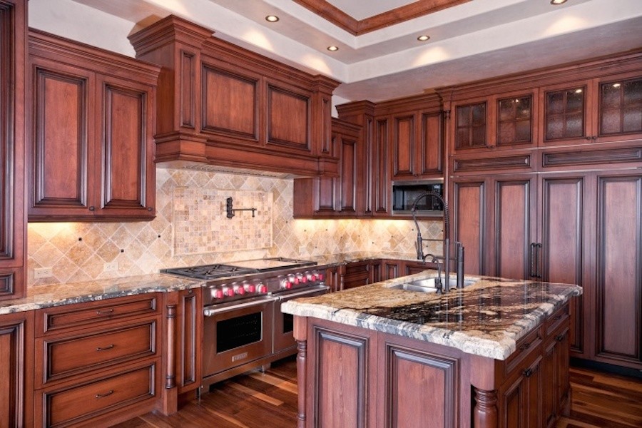 Exempel på ett avskilt, stort klassiskt kök, med en dubbel diskho, skåp i mellenmörkt trä, granitbänkskiva, beige stänkskydd, stänkskydd i terrakottakakel, integrerade vitvaror, mellanmörkt trägolv, en köksö och luckor med upphöjd panel
