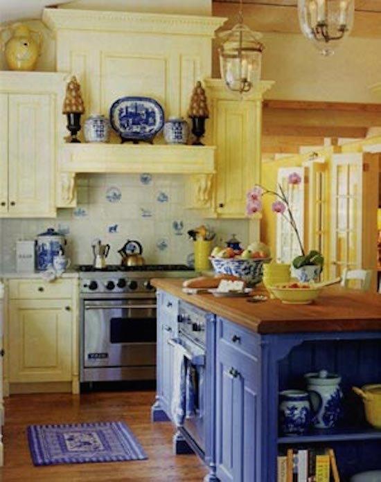Klassisk inredning av ett stort l-kök, med luckor med upphöjd panel, gula skåp, träbänkskiva, vitt stänkskydd, stänkskydd i porslinskakel, rostfria vitvaror, mellanmörkt trägolv och en köksö