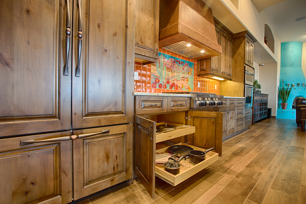 Example of a large southwest single-wall eat-in kitchen design in Phoenix with raised-panel cabinets, medium tone wood cabinets, granite countertops, orange backsplash, ceramic backsplash and stainless steel appliances