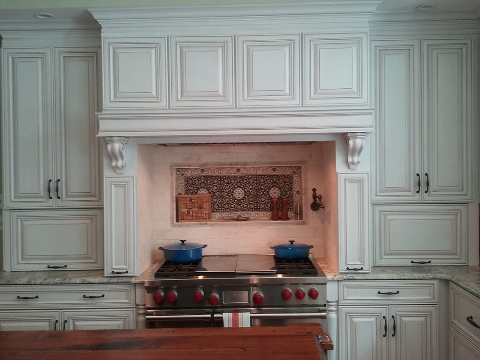 Imagen de cocina tradicional con fregadero sobremueble, armarios con paneles con relieve, puertas de armario beige, encimera de madera, salpicadero beige y salpicadero de azulejos de piedra