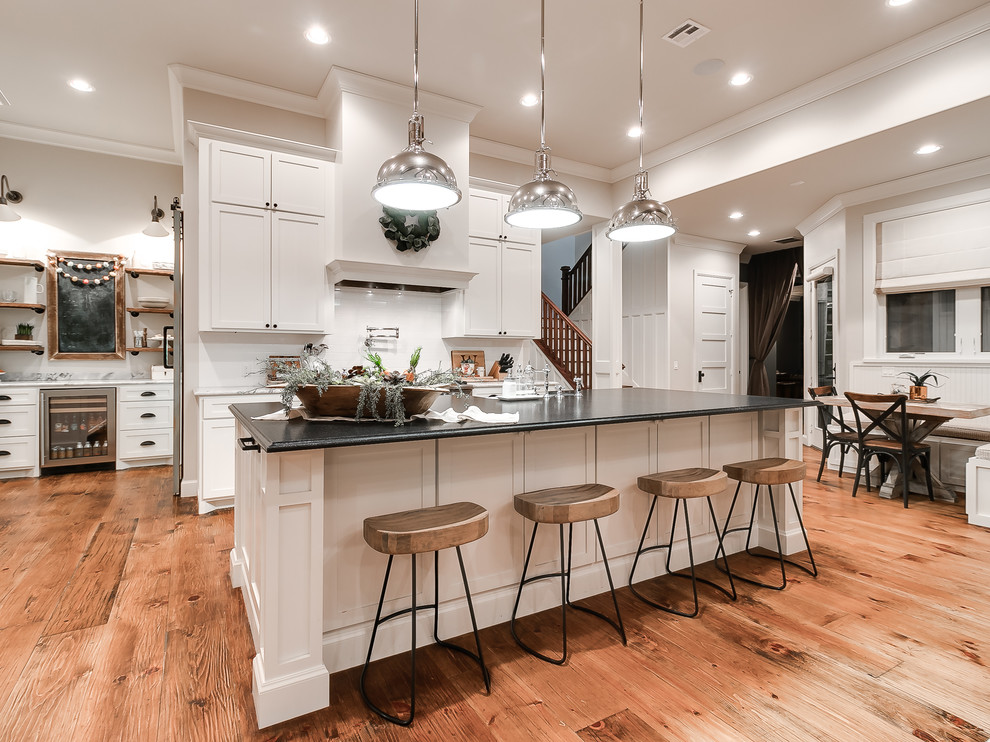Zweizeilige Country Wohnküche mit Schrankfronten im Shaker-Stil, weißen Schränken, Küchenrückwand in Weiß, dunklem Holzboden, Kücheninsel und braunem Boden in Oklahoma City