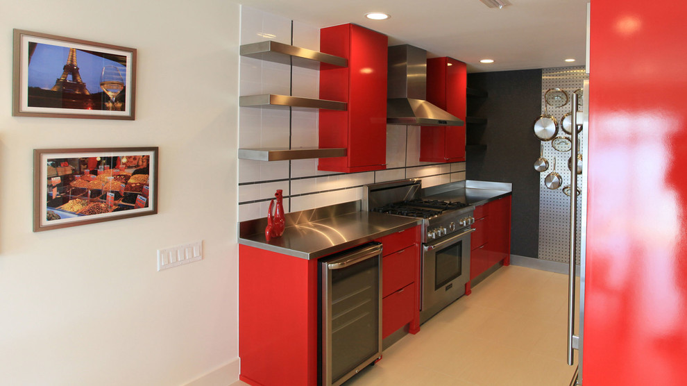 Inspiration for a large modern galley ceramic tile eat-in kitchen remodel in Dallas with flat-panel cabinets, red cabinets, stainless steel countertops, white backsplash and stainless steel appliances
