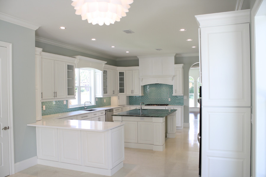 Large beach style u-shaped eat-in kitchen photo in Miami with white cabinets, blue backsplash, stainless steel appliances and an island