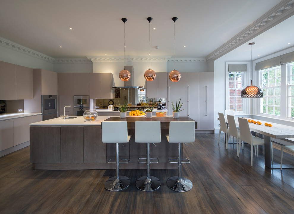 Moderne Küche mit Unterbauwaschbecken, flächenbündigen Schrankfronten, beigen Schränken, Küchengeräten aus Edelstahl, dunklem Holzboden und Kücheninsel in London