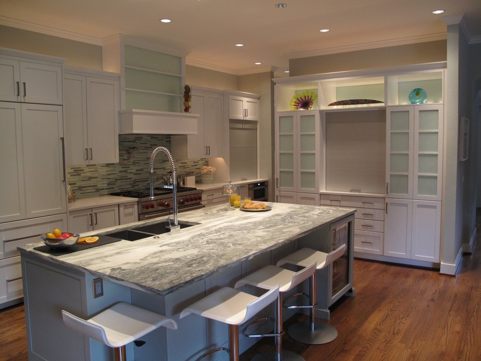 Inspiration for a large transitional l-shaped medium tone wood floor and brown floor open concept kitchen remodel in Dallas with an undermount sink, recessed-panel cabinets, white cabinets, marble countertops, multicolored backsplash, glass tile backsplash, stainless steel appliances and an island