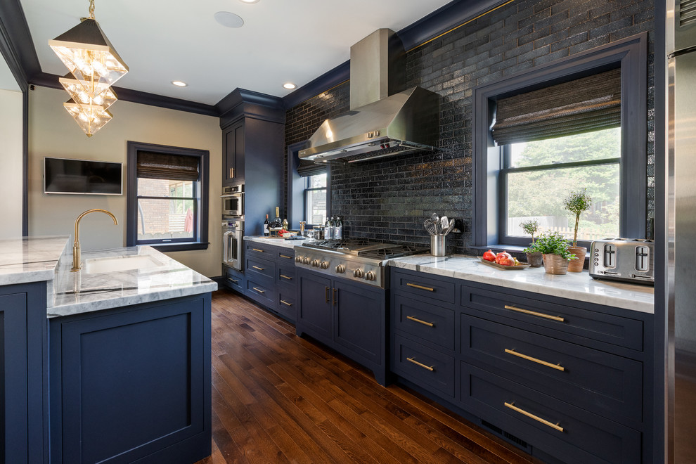 Design ideas for a classic galley kitchen in Detroit with a submerged sink, shaker cabinets, blue cabinets, black splashback, metro tiled splashback, stainless steel appliances, dark hardwood flooring, an island, brown floors and white worktops.