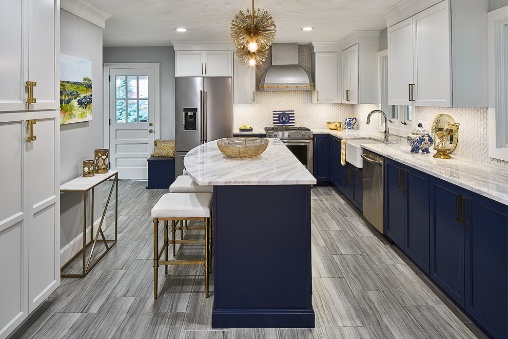 This is an example of a medium sized traditional l-shaped kitchen/diner in Charlotte with a belfast sink, recessed-panel cabinets, blue cabinets, marble worktops, white splashback, mosaic tiled splashback, stainless steel appliances, porcelain flooring, an island, grey floors and white worktops.