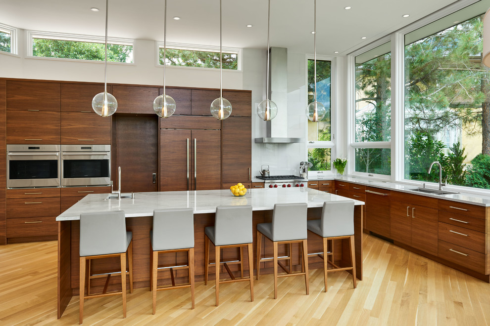 This is an example of a contemporary l-shaped kitchen in Other with a submerged sink, flat-panel cabinets, dark wood cabinets, light hardwood flooring, an island and beige floors.