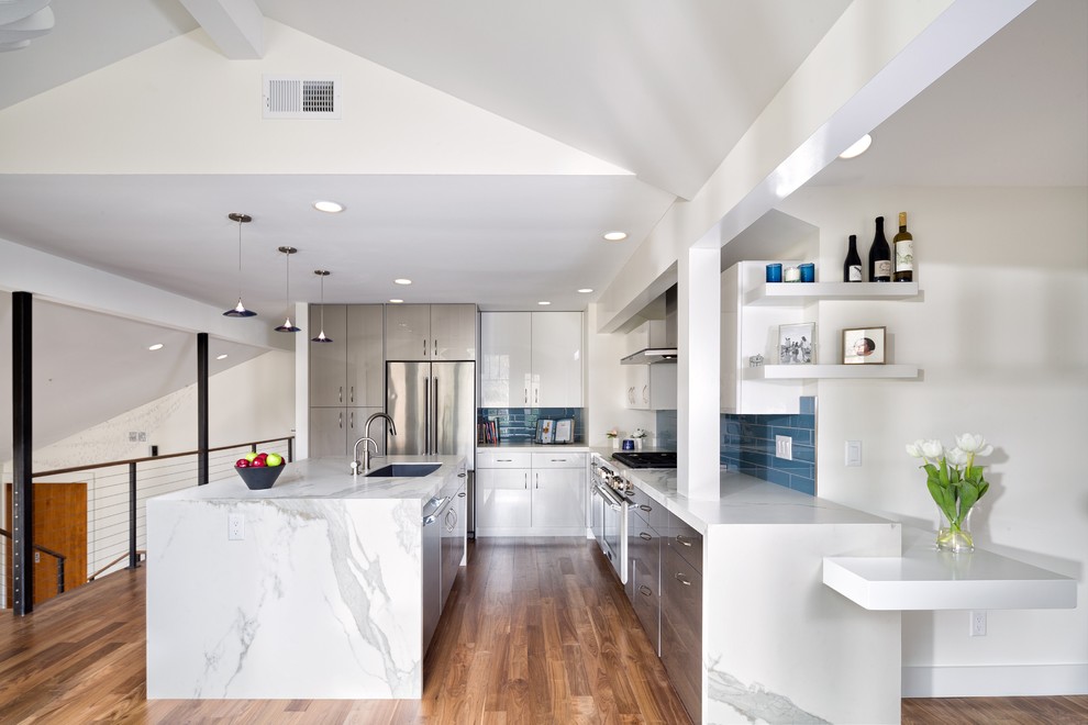 Inspiration for a mid-sized transitional l-shaped medium tone wood floor and brown floor eat-in kitchen remodel in Denver with an undermount sink, flat-panel cabinets, gray cabinets, blue backsplash, glass tile backsplash, stainless steel appliances and an island