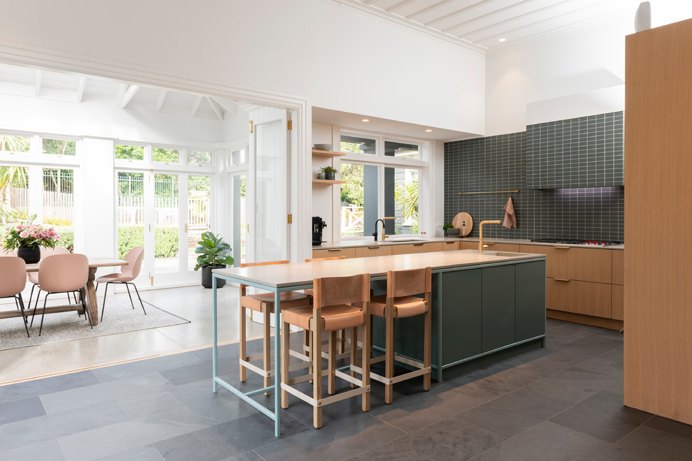 Imagen de cocina escandinava con fregadero de un seno, armarios con paneles lisos, puertas de armario de madera clara, salpicadero verde, una isla, suelo gris y encimeras grises