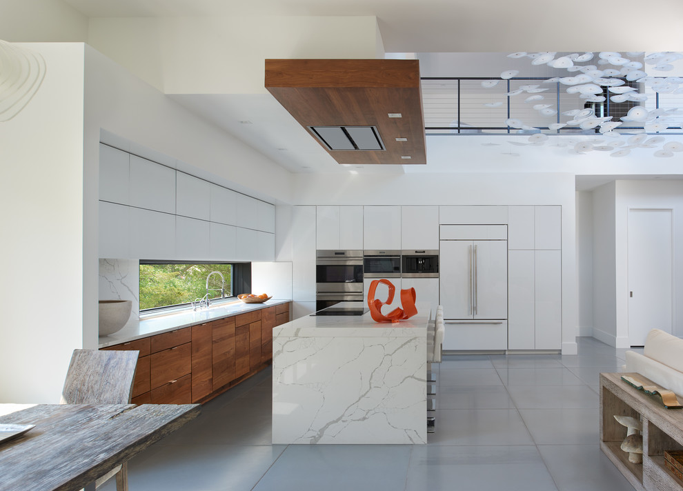 Moderne Küche in L-Form mit flächenbündigen Schrankfronten, hellbraunen Holzschränken, Küchengeräten aus Edelstahl, Kücheninsel, grauem Boden und weißer Arbeitsplatte in Washington, D.C.