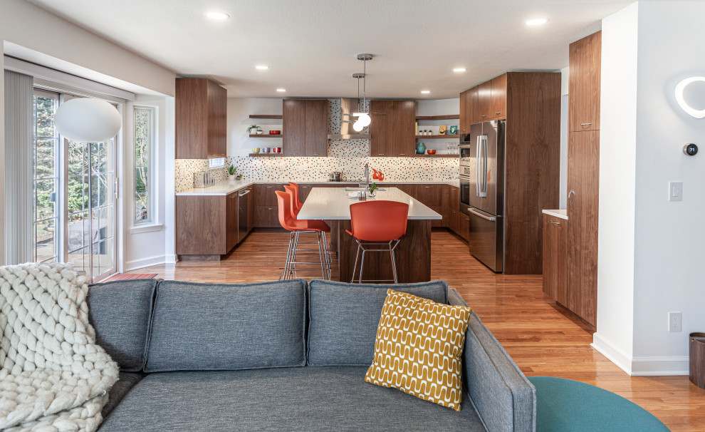 Photo of a large midcentury u-shaped kitchen/diner in Detroit with a submerged sink, flat-panel cabinets, dark wood cabinets, engineered stone countertops, multi-coloured splashback, ceramic splashback, stainless steel appliances, light hardwood flooring, an island, brown floors and white worktops.