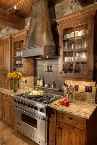 Diseño de cocina rural con armarios tipo vitrina, puertas de armario de madera oscura, encimera de granito, salpicadero marrón y electrodomésticos de acero inoxidable