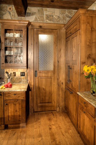 Exemple d'une cuisine américaine montagne en L et bois brun avec un placard à porte shaker, un plan de travail en granite, une crédence marron, une crédence en dalle de pierre et un électroménager en acier inoxydable.