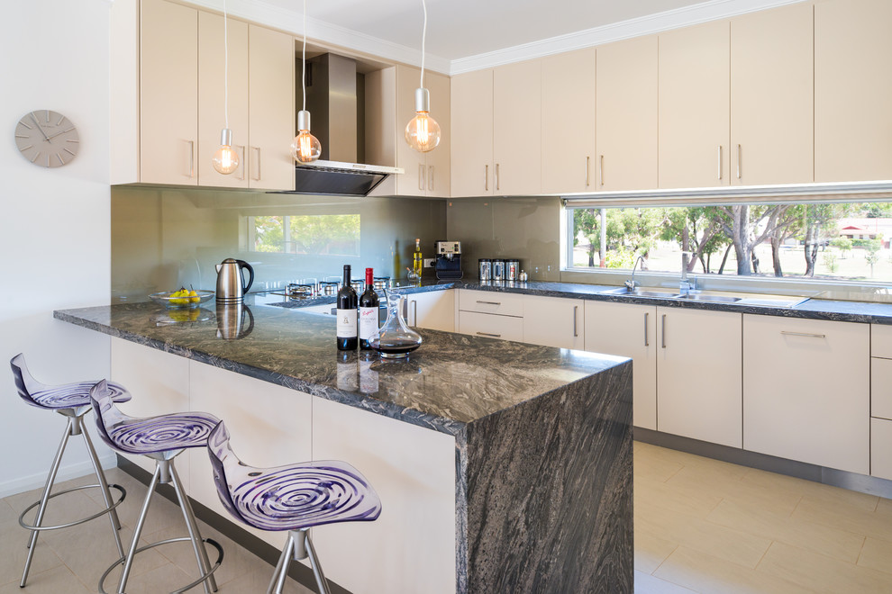 This is an example of a small contemporary u-shaped kitchen/diner in Perth with a double-bowl sink, flat-panel cabinets, beige cabinets, marble worktops, grey splashback, glass sheet splashback, stainless steel appliances and porcelain flooring.