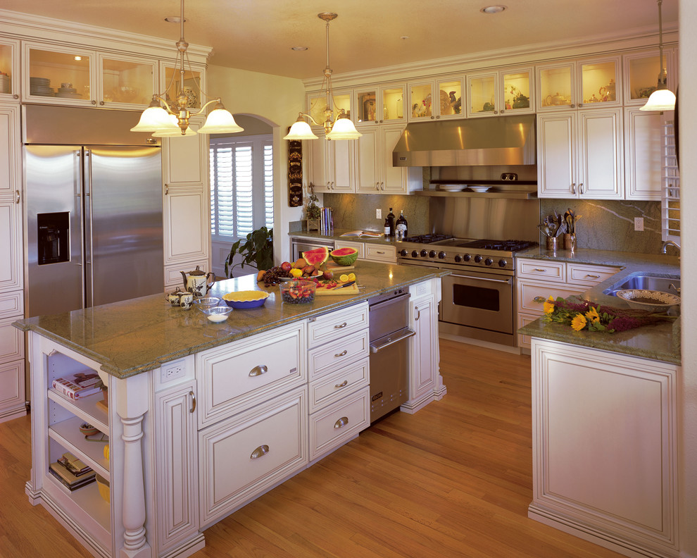 Example of a large classic u-shaped light wood floor open concept kitchen design in San Francisco with an undermount sink, raised-panel cabinets, yellow cabinets, granite countertops, green backsplash, stone slab backsplash, stainless steel appliances and an island