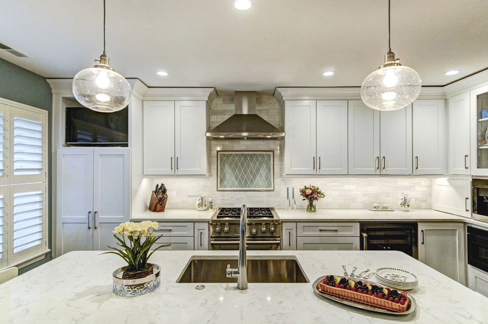 Idéer för mellanstora vintage vitt kök, med en undermonterad diskho, luckor med infälld panel, vita skåp, marmorbänkskiva, vitt stänkskydd, stänkskydd i marmor, rostfria vitvaror, mellanmörkt trägolv, en köksö och brunt golv