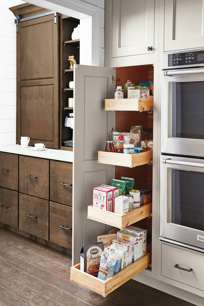 Idées déco pour une arrière-cuisine classique avec des portes de placard blanches, un électroménager en acier inoxydable, un sol en bois brun, îlot et un sol marron.