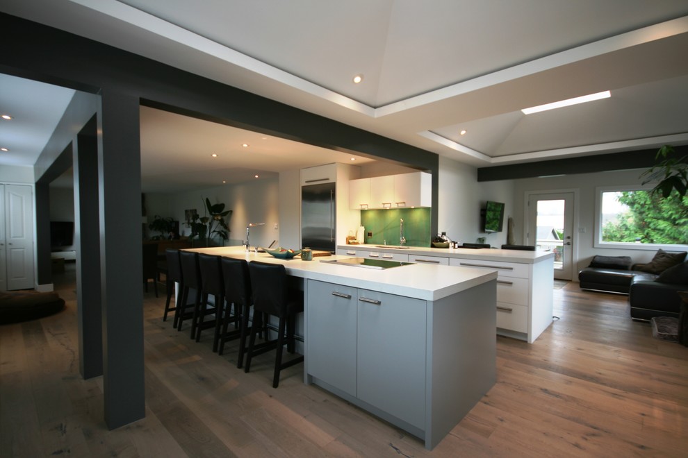 Exempel på ett stort modernt kök, med en undermonterad diskho, släta luckor, grå skåp, bänkskiva i kvartsit, grönt stänkskydd, stänkskydd i cementkakel, rostfria vitvaror, mellanmörkt trägolv och en köksö