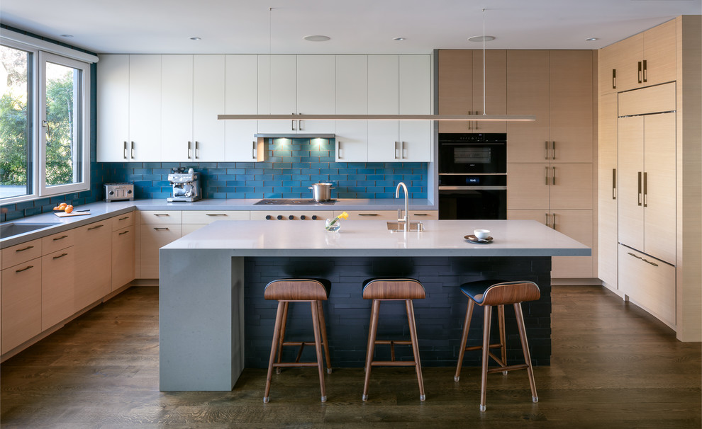 Kitchen - contemporary l-shaped dark wood floor and brown floor kitchen idea in San Francisco with flat-panel cabinets, light wood cabinets, quartz countertops, blue backsplash, paneled appliances, an island, gray countertops, an undermount sink and subway tile backsplash