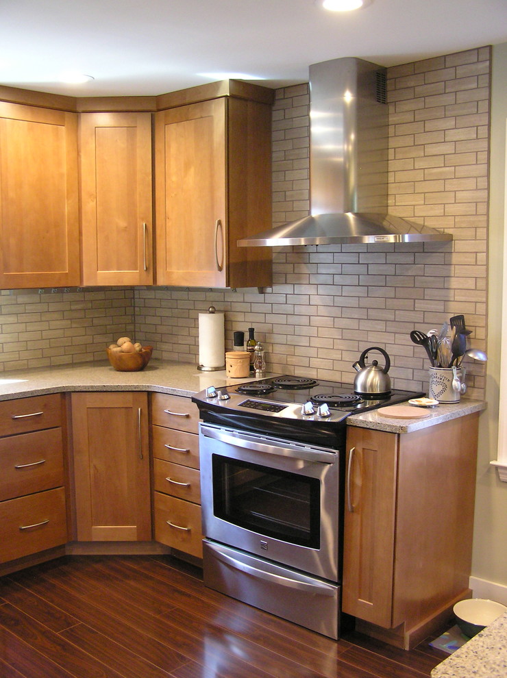 Example of a mid-sized transitional l-shaped eat-in kitchen design in Other with two islands, shaker cabinets, medium tone wood cabinets, quartz countertops, black backsplash, porcelain backsplash, stainless steel appliances and an undermount sink