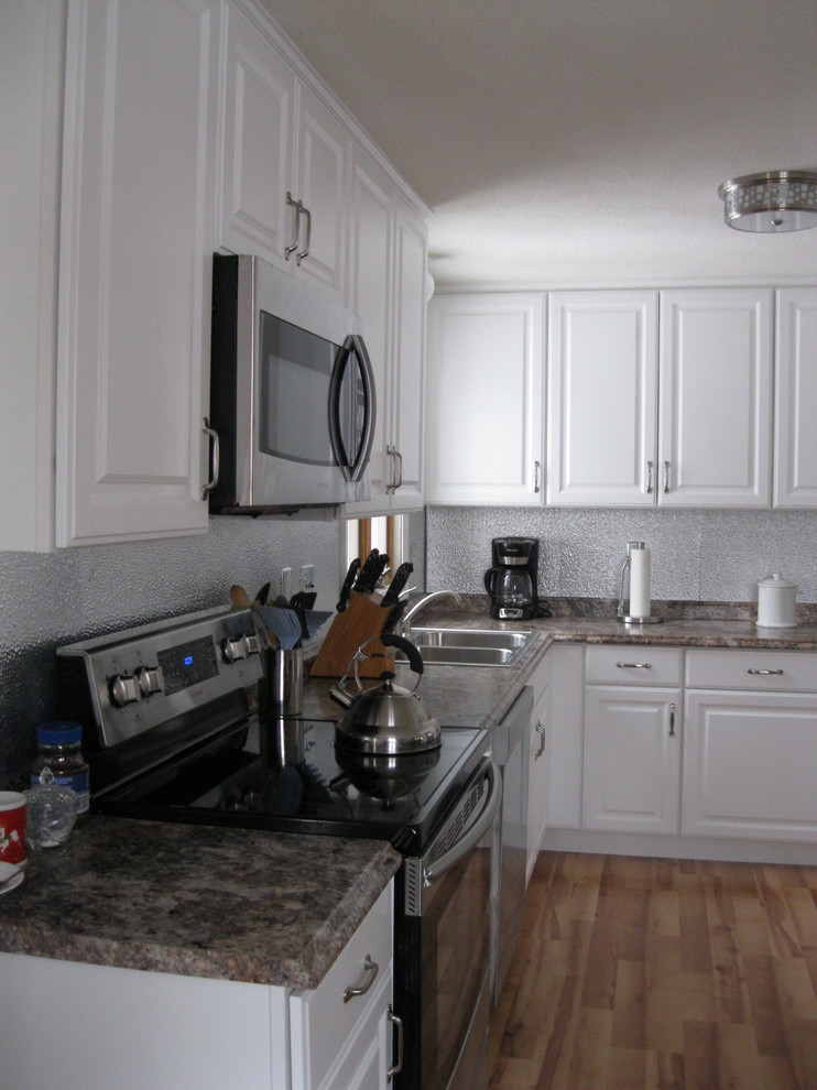Idéer för att renovera ett mellanstort vintage kök, med luckor med upphöjd panel, gula skåp, laminatbänkskiva, stänkskydd med metallisk yta, spegel som stänkskydd, rostfria vitvaror och en nedsänkt diskho