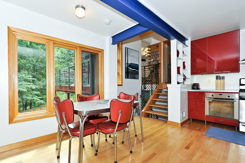 ワシントンD.C.にあるコンテンポラリースタイルのおしゃれなダイニングキッチン (フラットパネル扉のキャビネット、赤いキャビネット、シルバーの調理設備) の写真