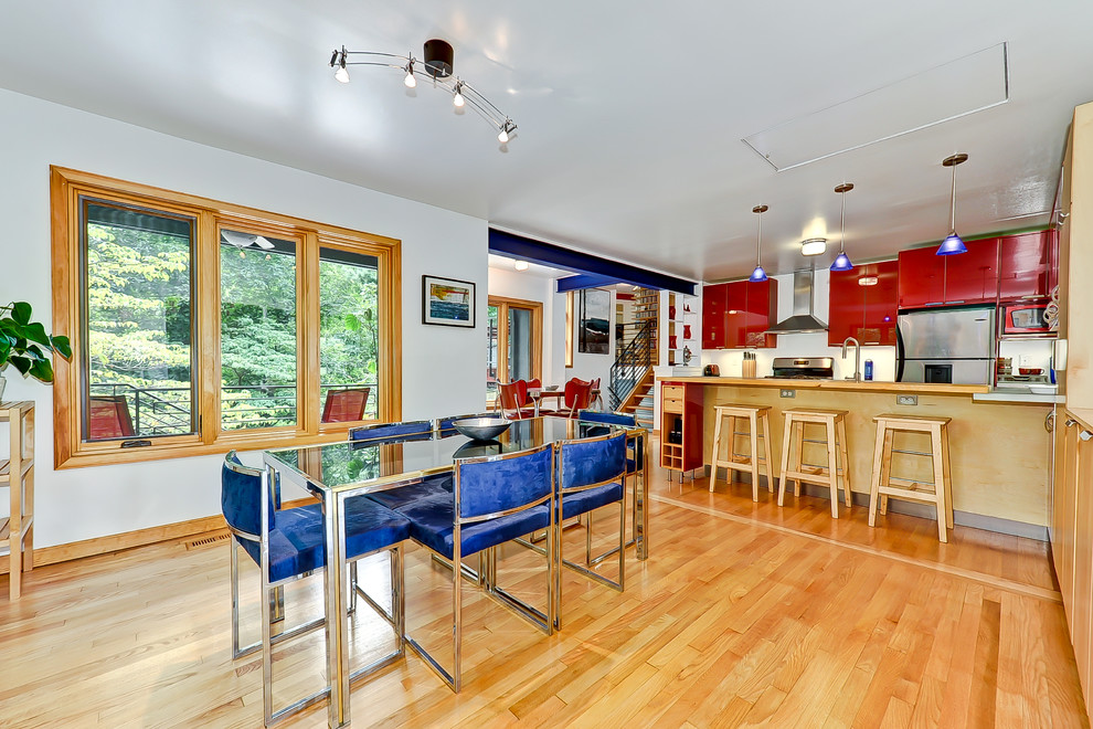 Источник вдохновения для домашнего уюта: параллельная кухня в современном стиле с обеденным столом, плоскими фасадами, красными фасадами и техникой из нержавеющей стали