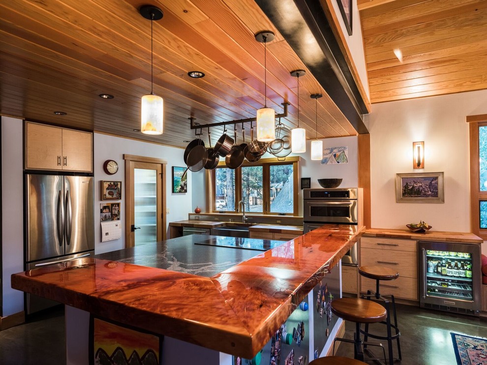 Large arts and crafts l-shaped concrete floor and black floor eat-in kitchen photo in Other with a farmhouse sink, flat-panel cabinets, light wood cabinets, marble countertops, black backsplash, marble backsplash, stainless steel appliances, an island and black countertops