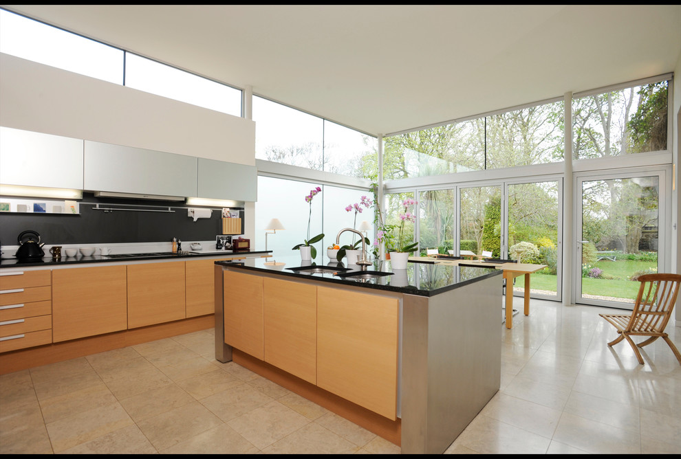 Photo of a medium sized contemporary l-shaped kitchen/diner in Edinburgh with a double-bowl sink, flat-panel cabinets, light wood cabinets, engineered stone countertops, black splashback, stone slab splashback, stainless steel appliances, porcelain flooring and an island.