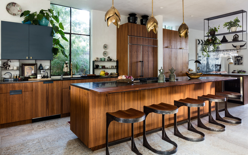 Aménagement d'une cuisine ouverte encastrable éclectique en bois brun avec un placard à porte plane, îlot, un sol multicolore, plan de travail noir et fenêtre au-dessus de l'évier.