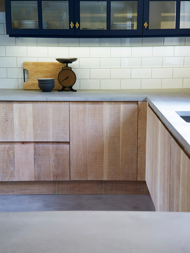 Inspiration for an urban u-shaped open plan kitchen in Other with a double-bowl sink, flat-panel cabinets, light wood cabinets, concrete worktops, white splashback, ceramic splashback, stainless steel appliances, concrete flooring and a breakfast bar.