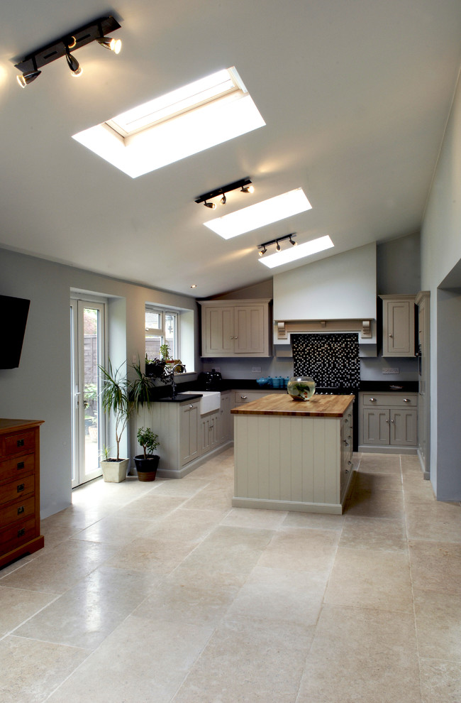 Example of a mid-sized minimalist l-shaped limestone floor eat-in kitchen design in Other with a farmhouse sink, recessed-panel cabinets, gray cabinets, quartzite countertops, multicolored backsplash, mosaic tile backsplash, paneled appliances and an island