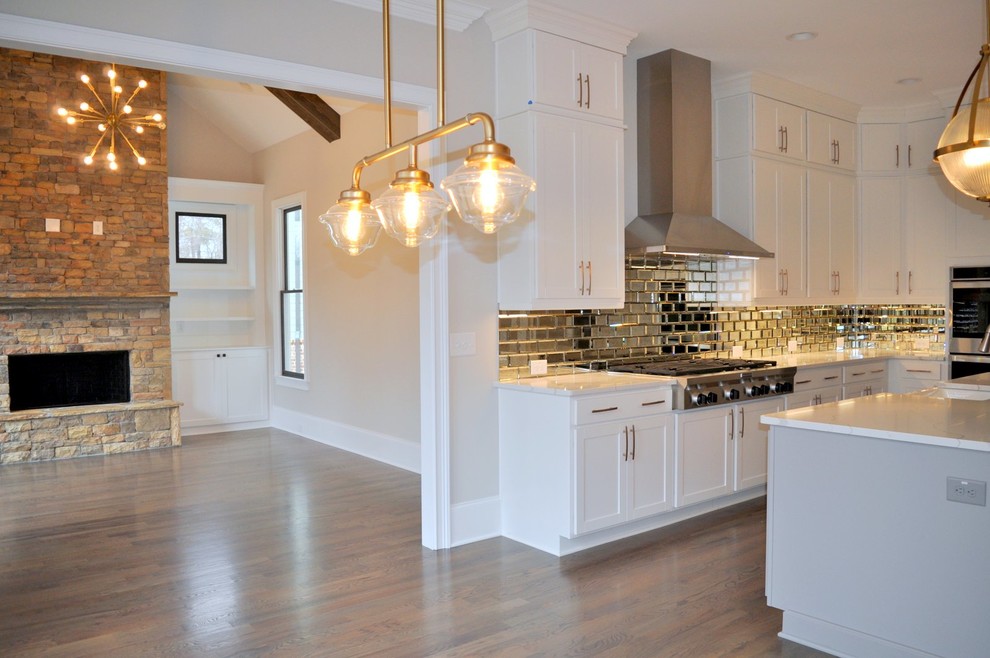 Foto på ett lantligt vit kök, med en rustik diskho, släta luckor, vita skåp, bänkskiva i kvartsit, stänkskydd med metallisk yta, stänkskydd i glaskakel, rostfria vitvaror, mellanmörkt trägolv, en köksö och brunt golv