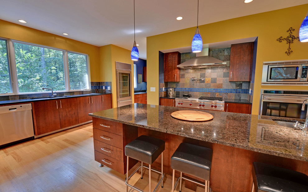 Moderne Küche mit flächenbündigen Schrankfronten, hellbraunen Holzschränken, bunter Rückwand, Küchengeräten aus Edelstahl und Rückwand aus Schiefer in Atlanta