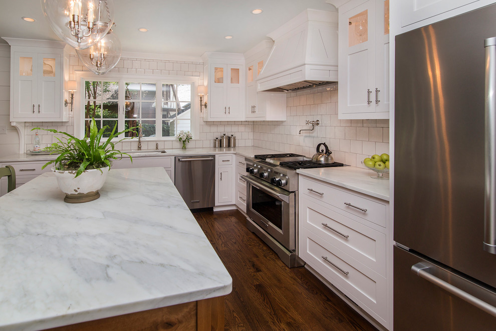 Eat-in kitchen - transitional medium tone wood floor eat-in kitchen idea in Charlotte with an island, a double-bowl sink, shaker cabinets, white cabinets, marble countertops, white backsplash, ceramic backsplash and stainless steel appliances
