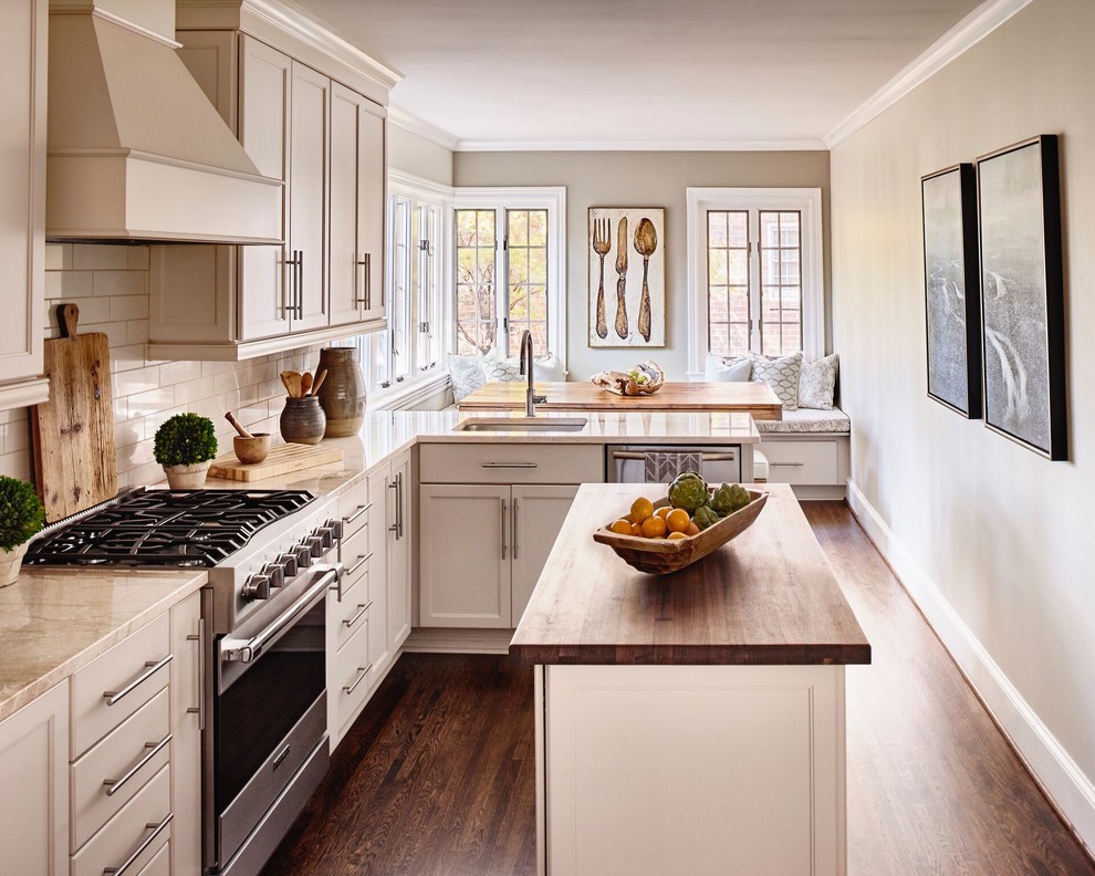 Foto på ett mellanstort funkis kök, med skåp i shakerstil, vita skåp, en köksö, en undermonterad diskho, vitt stänkskydd, stänkskydd i tunnelbanekakel, rostfria vitvaror, mörkt trägolv och brunt golv